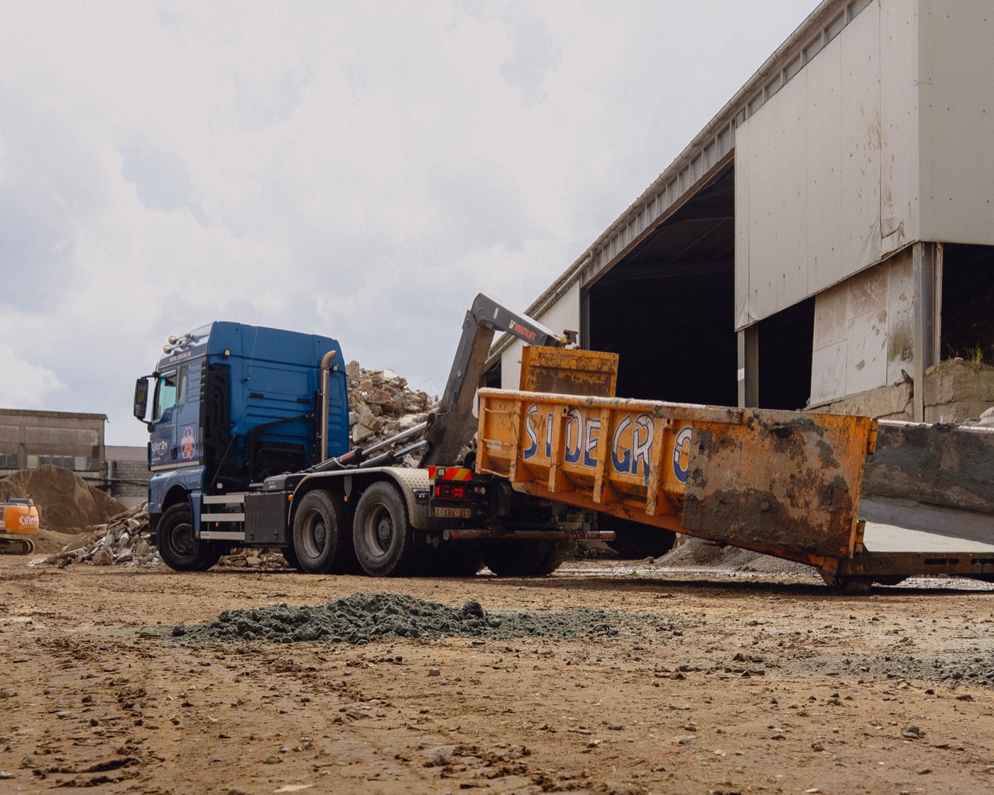 Sidegro-vrachtwagen laadt een container in de loods